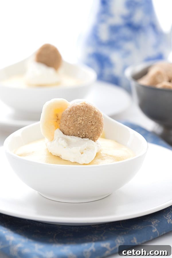 Keto Banana Pudding presented beautifully in small white dessert cups, with a soft blue vase in the background, hinting at a cozy home setting, ready for enjoyment.
