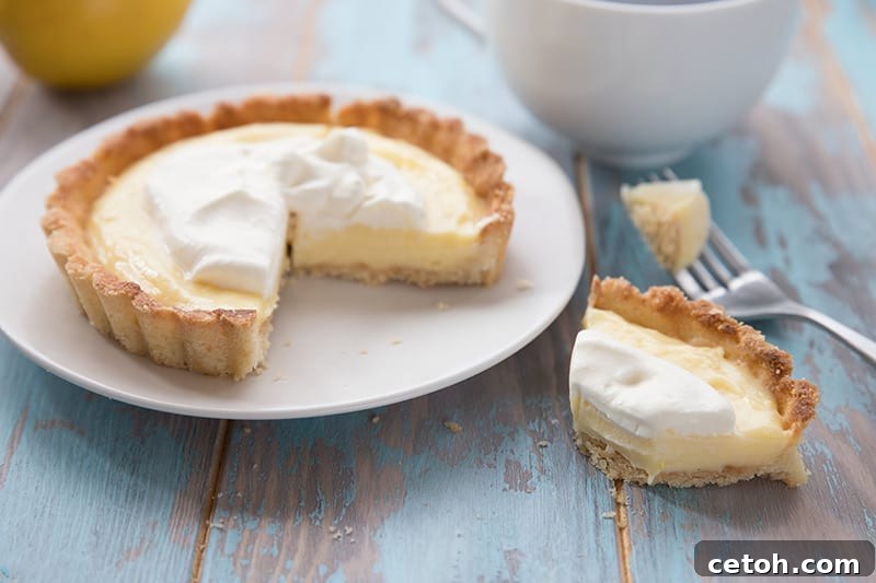Keto Couple's Kitchen 2 A vibrant Keto Lemon Curd Tart for Two, beautifully plated on a white dish, set against a rustic blue wooden table. Perfect for a mindful dessert.