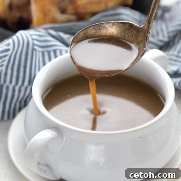 A ladle drizzling keto gravy into a white bowl.