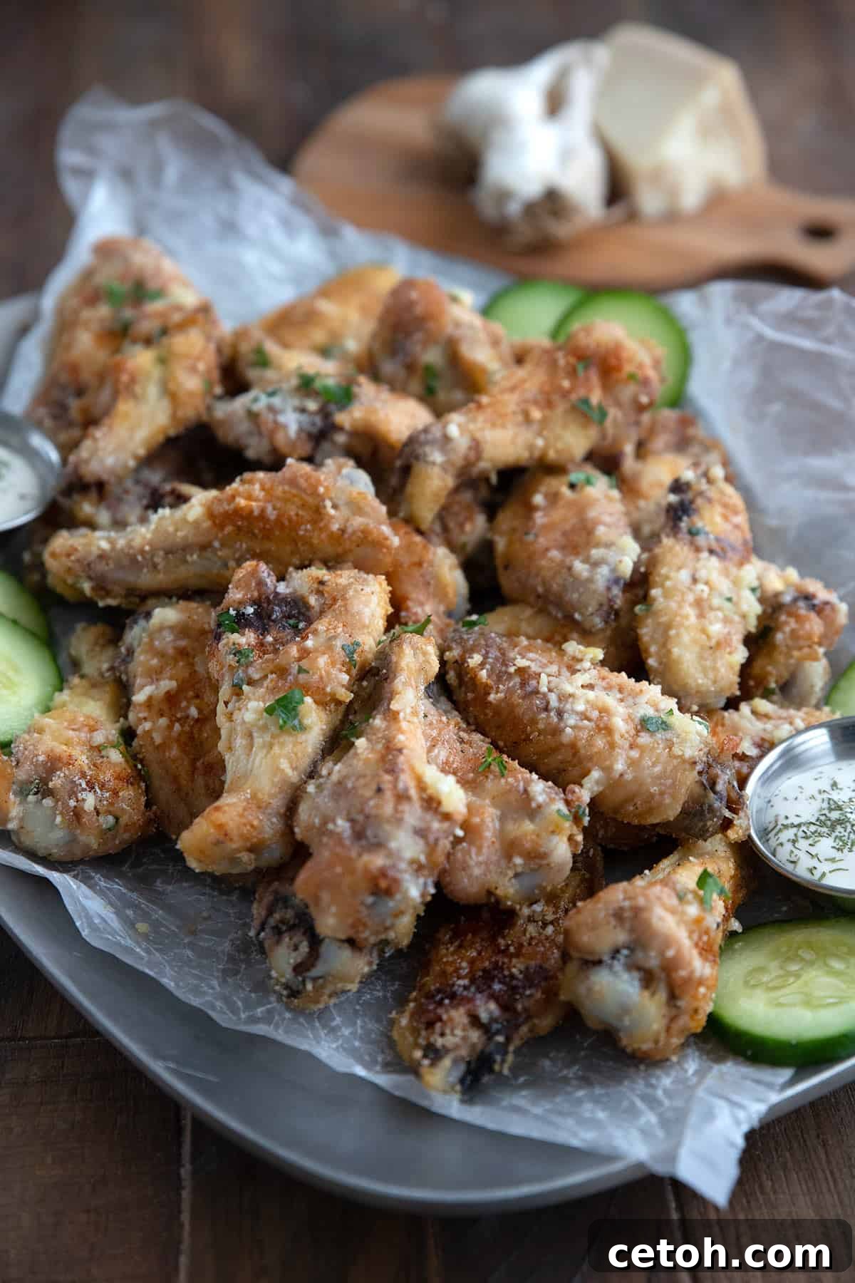 A tray filled with perfectly golden and crispy keto chicken wings, seasoned with garlic and Parmesan, resting on a brown wooden table.
