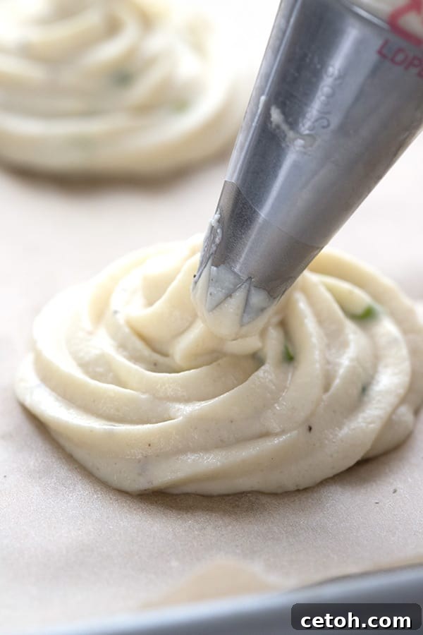 Keto Duchess Whipped Swirls 3 Close up shot of keto duchess cauliflower being piped onto parchment paper