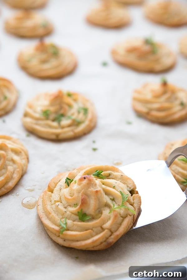 Keto Duchess Whipped Swirls 5 A spatula lifting duchess cauliflower potatoes off a baking sheet.