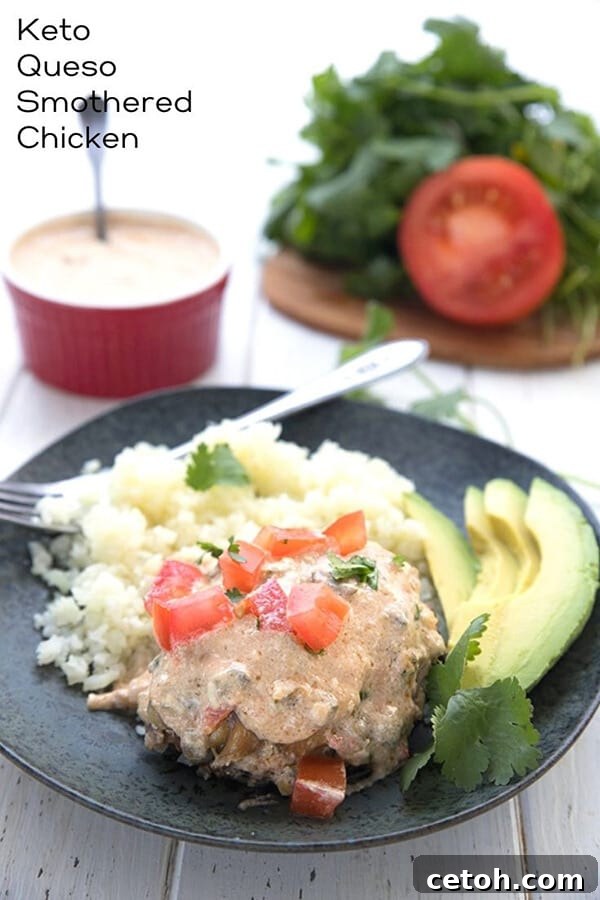 A perfectly cooked piece of Keto Slow Cooker Smothered Chicken on a black plate, served alongside fluffy cauliflower rice and a slice of fresh avocado, highlighting the rich queso sauce.