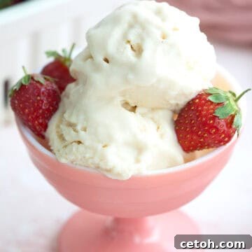Two scoops of keto ice cream with strawberries in a pink ice cream dish.