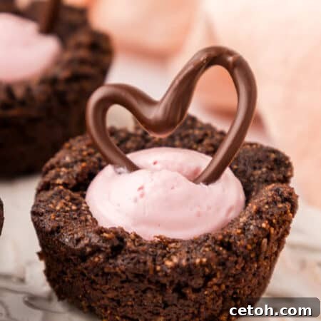 Close up shot of a Keto Raspberry Cheesecake Cookie Cups on a white plate with a chocolate heart on top.
