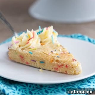 A slice of keto cookie cake on a white plate over a blue patterned napkin