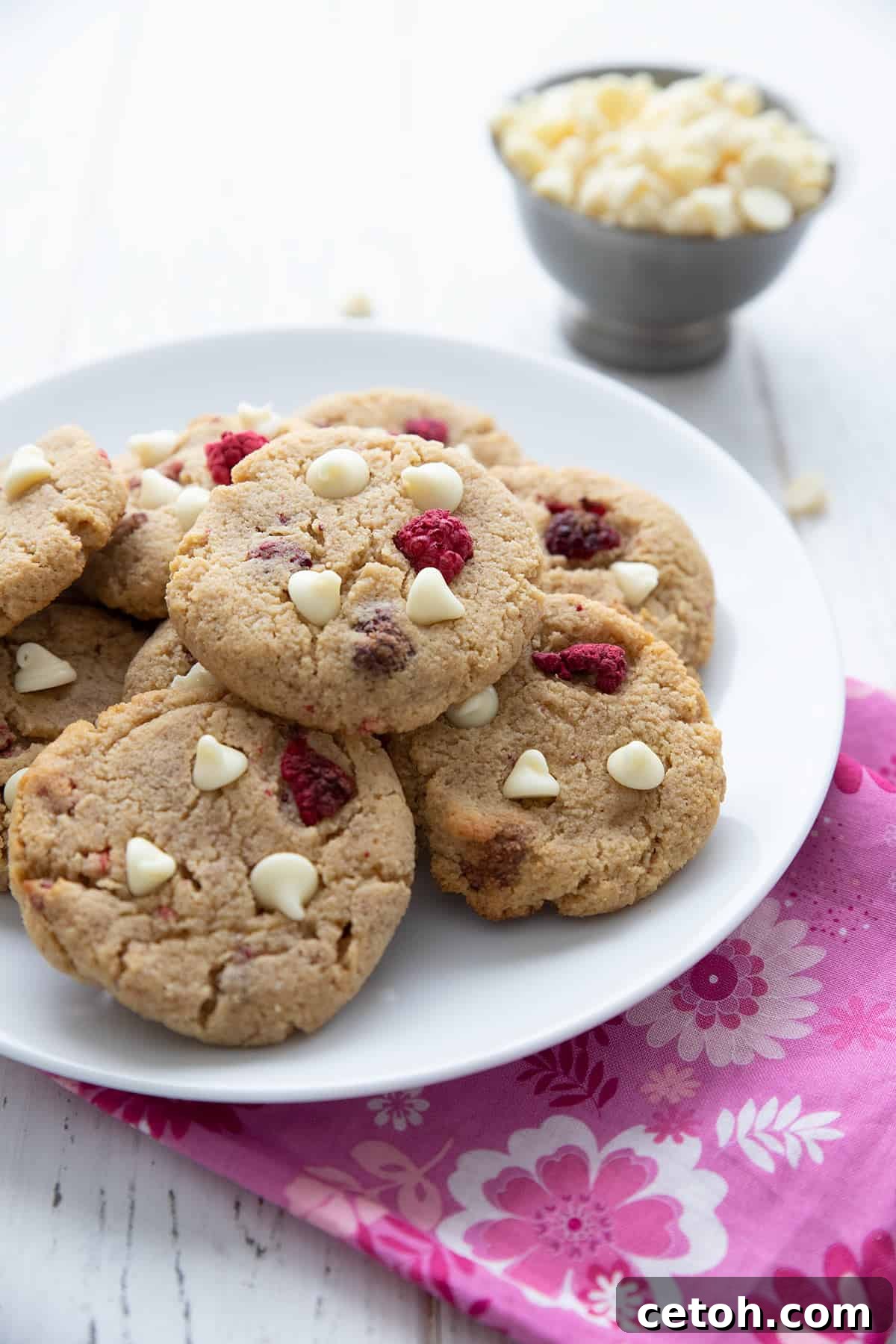 Keto raspberry cheesecake cookies on a white plate over a pink patterned napkin.