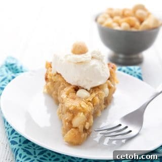 A slice of Keto White Chocolate Macadamia Nut Pie on a white plate with a bowl of macadamias in the background.