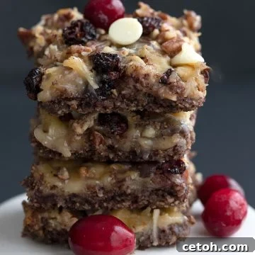 A stack of keto cranberry magic bars on a white cake stand.