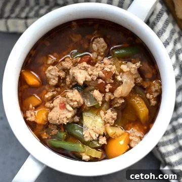 Top down image of keto Italian sausage soup in a white bowl with handles.
