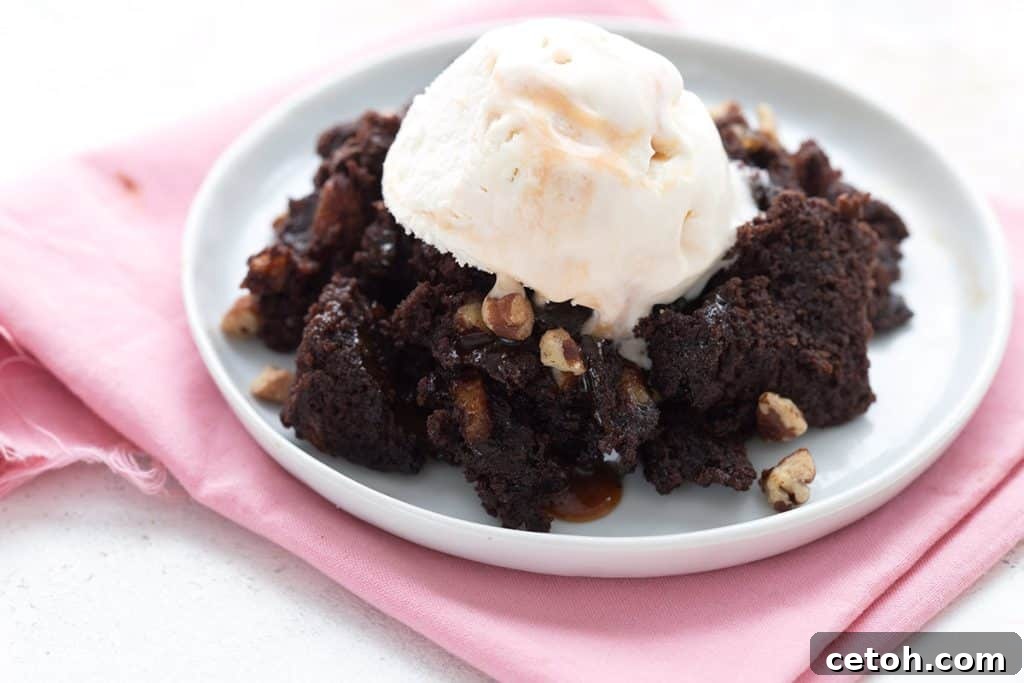 Keto turtle brownies on a white plate with a scoop of keto ice cream on top.