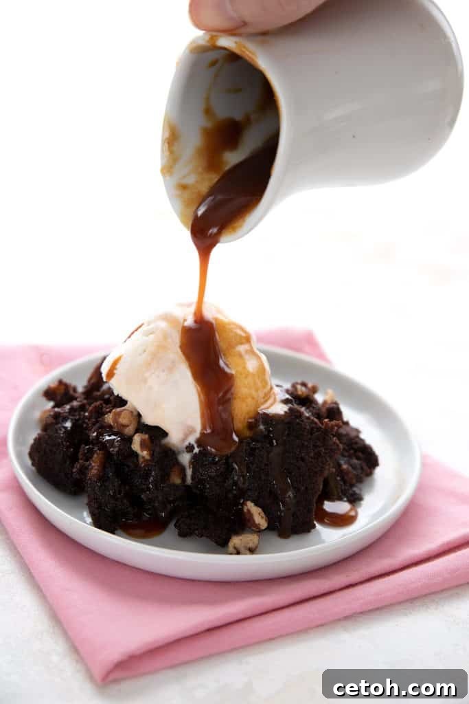 Pouring sugar free caramel sauce over a plate of keto brownies and ice cream.