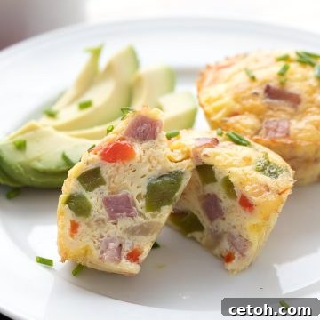A close-up shot of a Denver omelet egg muffin cut open to show the inside, showcasing the ham, peppers, and melted cheese.