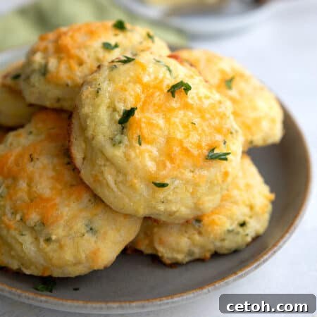 Keto Cheese Biscuits piled up on a grey plate on a white table top.