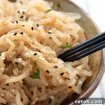 Close up shot of a bowl full of sesame shirataki noodles with chopsticks sticking out of it.