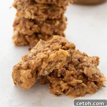 Two keto no bake cookies in front of a stack of more cookies, enticingly arranged.