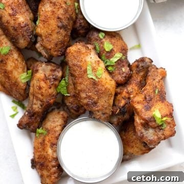 Top down image of Keto Cajun Wings on a white platter with bowls of dipping sauce.