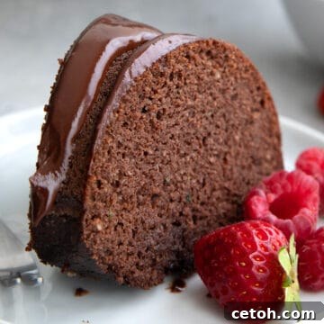 A slice of Keto Chocolate Zucchini Cake on a white plate with fresh berries.