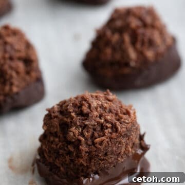 Close up shot of a chocolate dipped keto macaroon on a white tray.