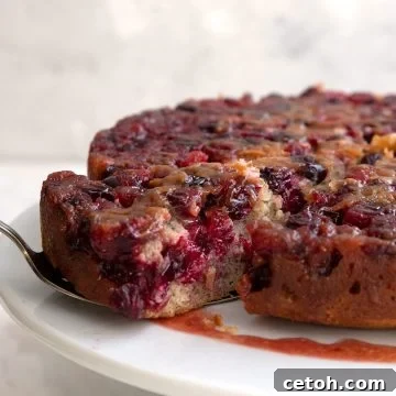 Cranberry Upside Down Cake with a slice being pulled away with a cake lifter.