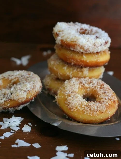 several low carb donuts topped with shredded coconut stacked on a plate