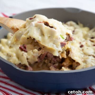 A wooden spoon lifting Reuben Casserole out of the pan.