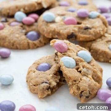 A pile of Keto Monster Cookies with one broken open in front.