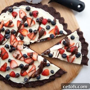 Top-down image of Keto Chocolate Cookie Pizza on a wooden cutting board with a pizza cutter.