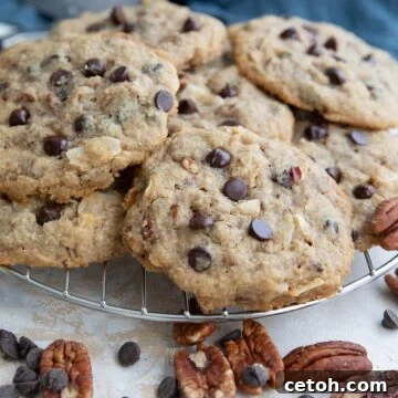 Keto Cowboy Cookies on a cooling rack with pecans and chocolate chips strewn around.