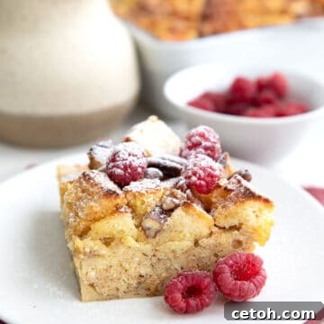A serving of Keto French Toast Casserole on a white plate over a muted red napkin, dusted with powdered sweetener.