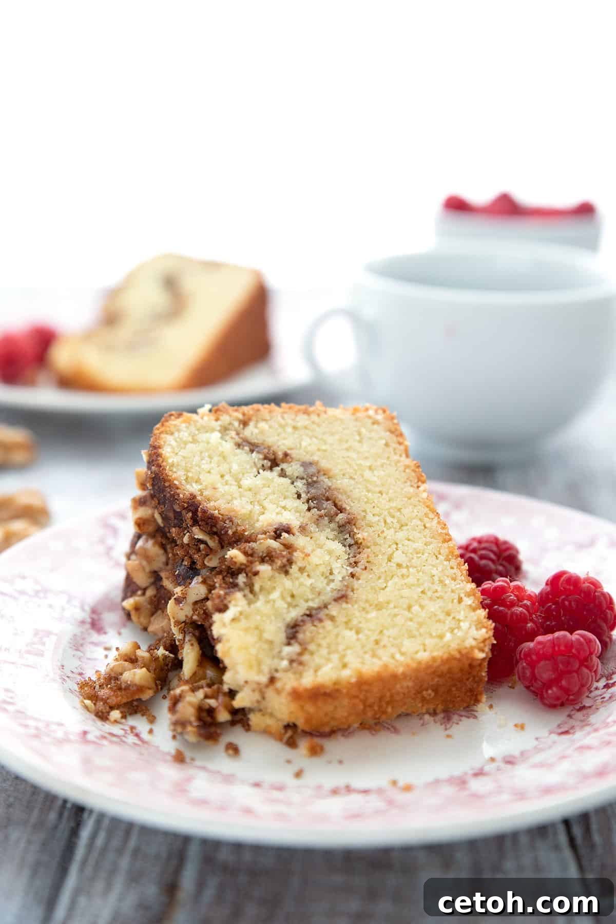 A slice of bakery style keto coffee cake on its side on a red patterned plate, showing the walnut cinnamon swirl.