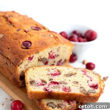 Zesty Keto Cranberry Orange Loaf 5 Keto Cranberry Orange Bread on a cutting board with two slices cut in front.