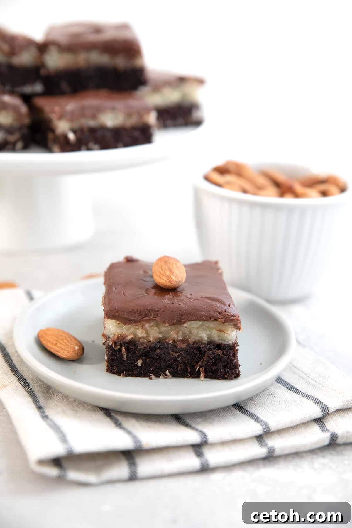 An Almond Joy Brownie on a white plate over a white and blue striped napkin.