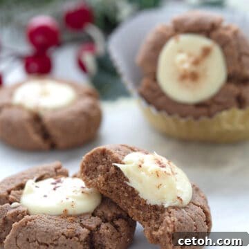 Keto Gingerbread White Chocolate Thumbprint Cookies on a white table with a bite taken out of one.