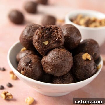 A white bowl filled with low carb protein balls, with a bite taken out of the top one.