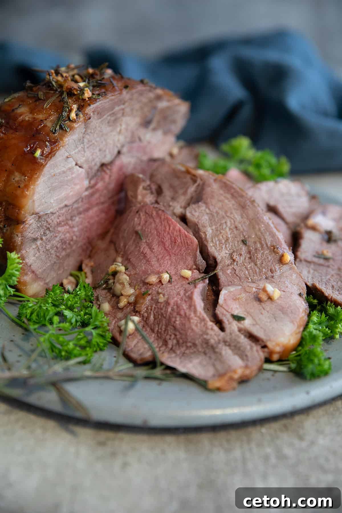 Fragrant Moroccan Lamb Stew 2 Sliced leg of lamb on a gray plate on a concrete table.