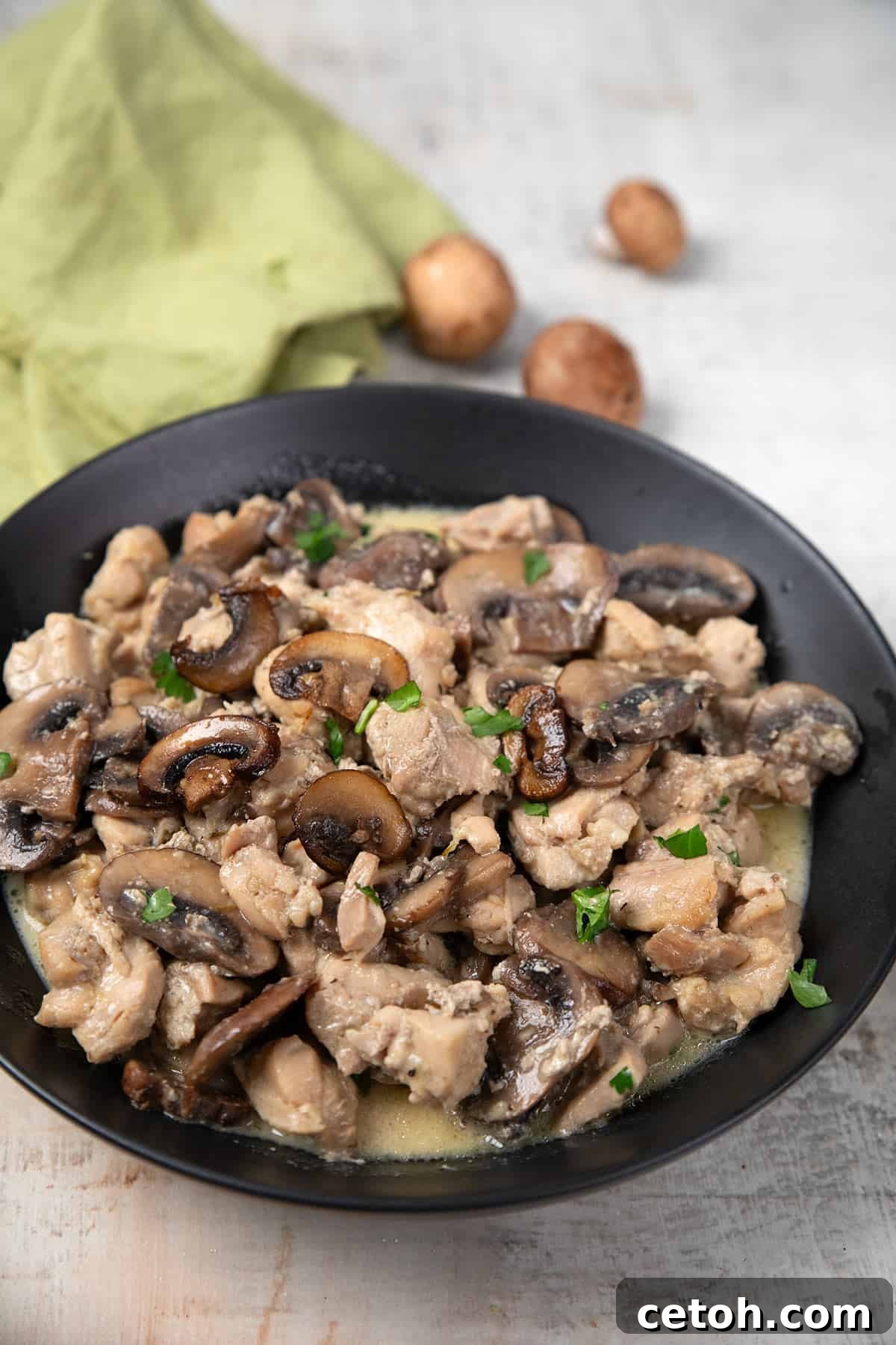 Instant Pot Mushroom Chicken in a black bowl on a weathered grey table.