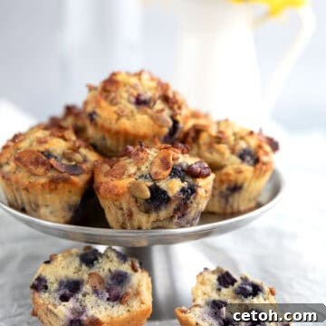 A stack of low carb granola muffins on a metal cake stand with one broken open in front.