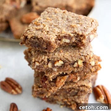 A stack of chewy keto pecan bars with a bite taken out of the top one, perfect for a low-carb treat.