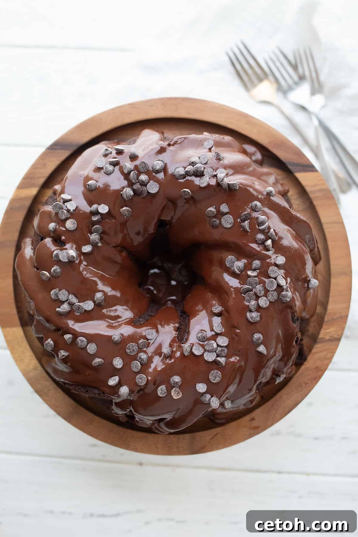A top-down view of the luscious Keto Chocolate Ricotta Cake, elegantly displayed on a wooden cake stand atop a white table.