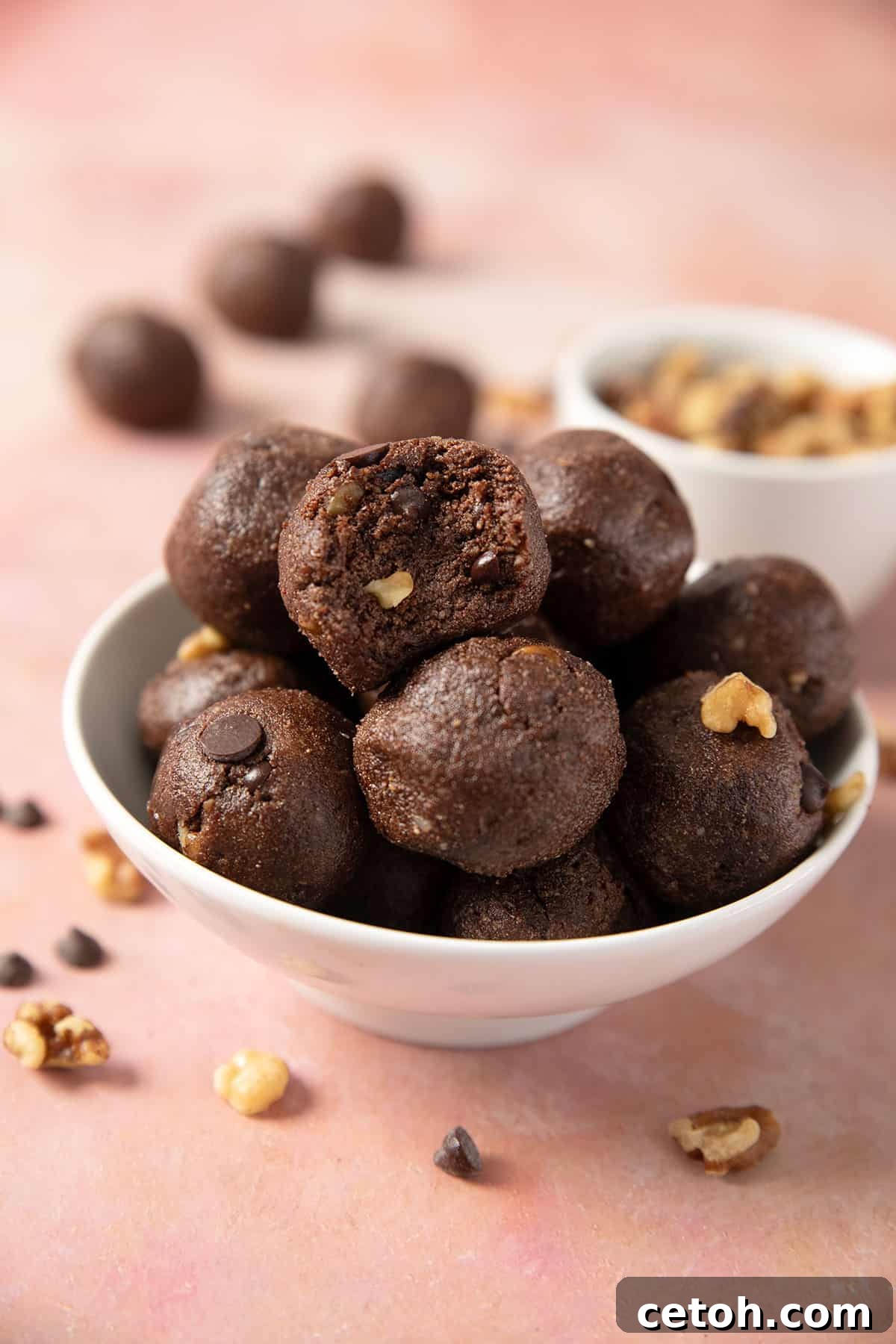A pristine white bowl brimming with delectable low-carb protein balls, with a satisfying bite taken from the topmost one.