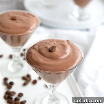 Glass dishes filled with protein mousse on a white platter, with coffee beans strewn around.