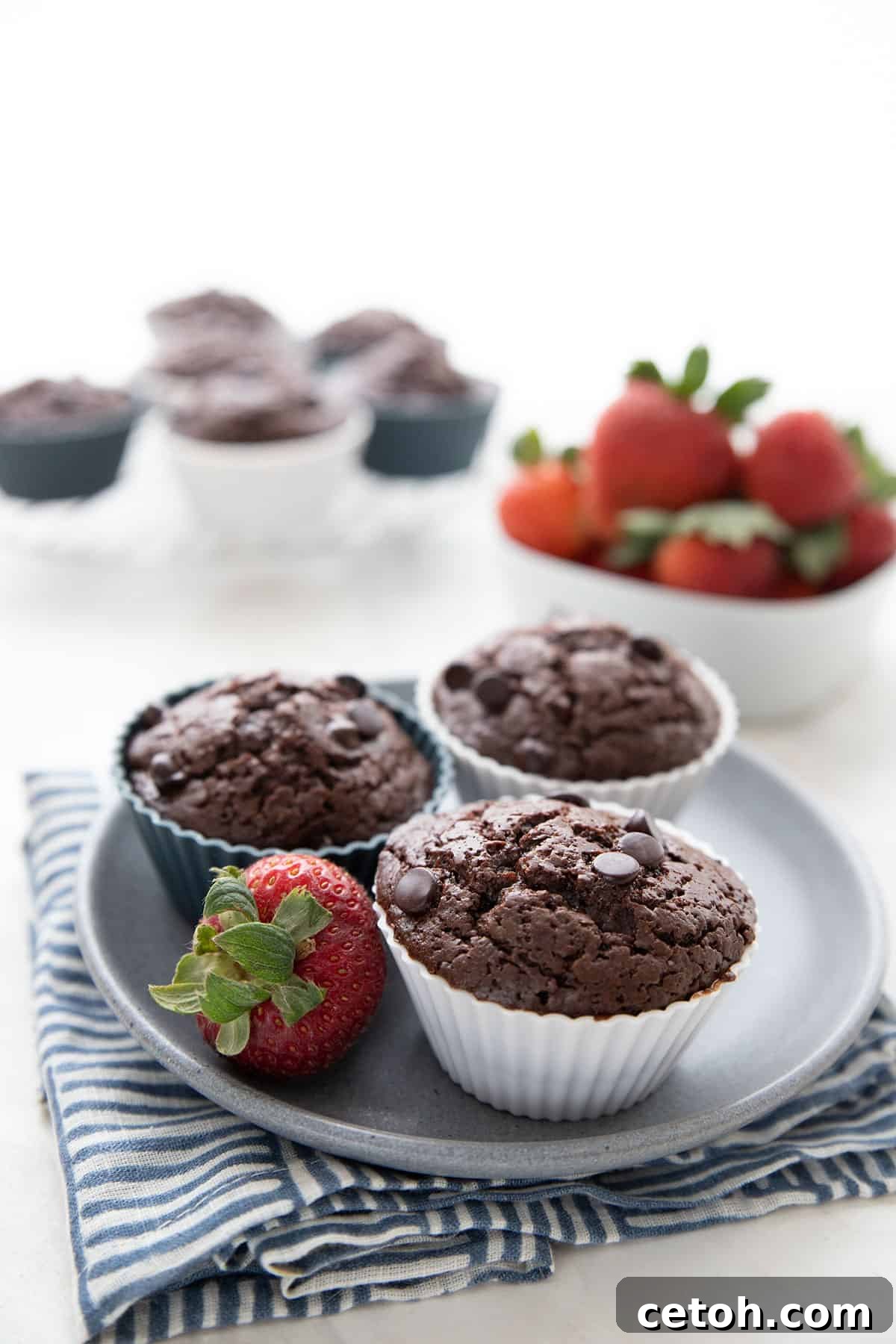 Effortless Keto Slow Cooker Breakfast Bake 4 Three perfectly baked keto protein muffins artfully arranged on a clean gray plate, resting on a charming blue striped napkin, ready to be enjoyed.
