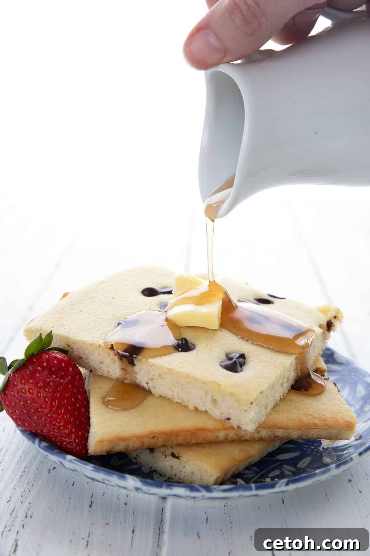 Effortless Keto Slow Cooker Breakfast Bake 3 A luscious stream of sugar-free maple syrup gracefully drizzles over a generous portion of golden Keto Sheet Pan Pancakes, highlighting their fluffy texture and enticing appeal.