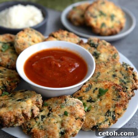 Spinach and Ricotta Fritters arranged on a white plate with a bowl of marinara sauce in the middle.