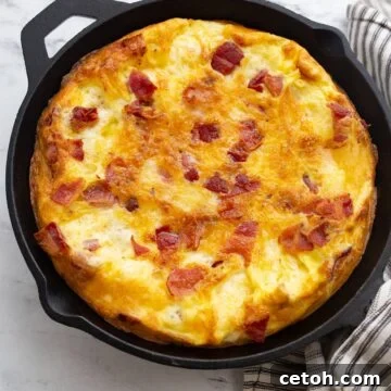 Puffy keto frittata in a cast iron skillet with a striped napkin.
