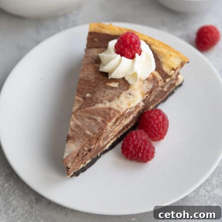 A slice of keto marble cheesecake on a white plate with raspberries.