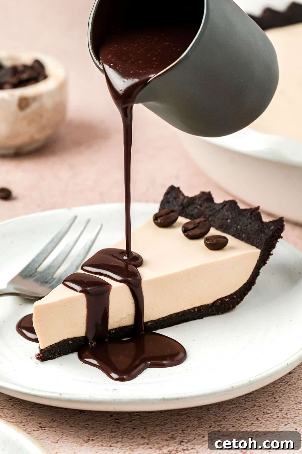 A small elegant pot gracefully pouring a stream of decadent chocolate sauce over a beautifully presented slice of Keto Cold Brew Coffee Pie, creating an enticing visual.