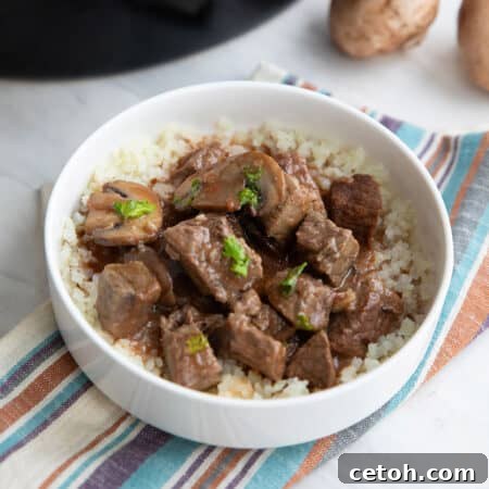 Slow Cooker Beef Tips in a white bowl over a striped napkin.
