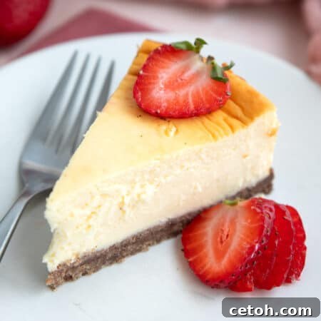 A slice of Keto Air Fryer Cheesecake on a white plate with sliced strawberries.